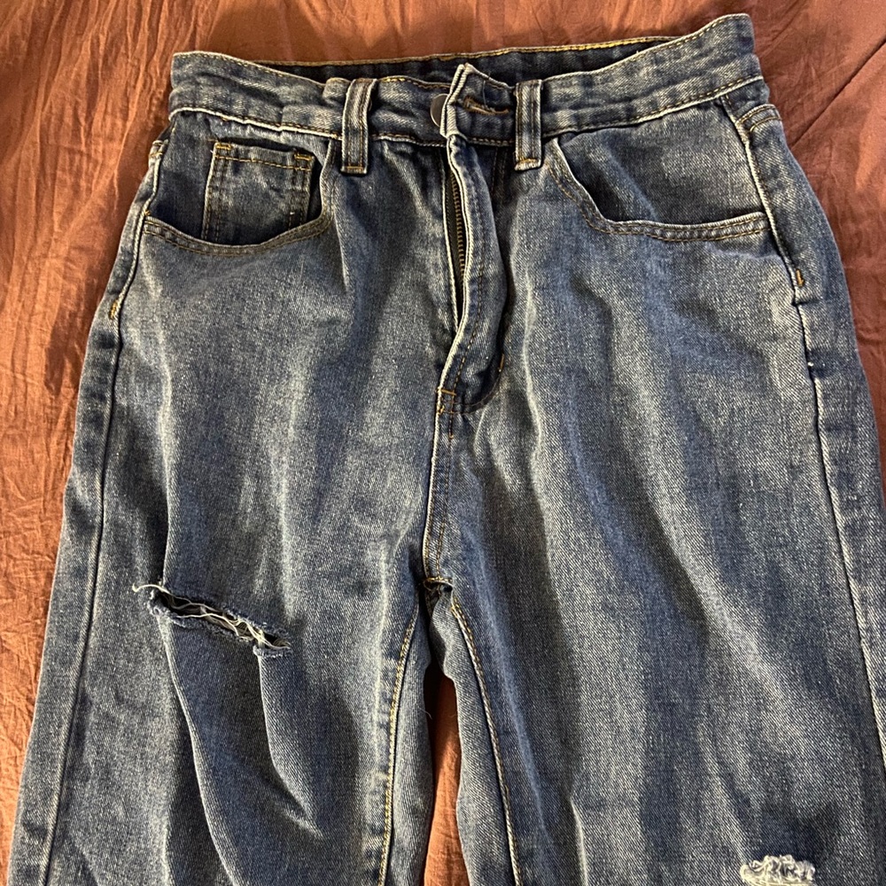 Dark blue, jeans, three tiny fashionable rips down by the knee